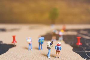 Miniature travelers walking on a world map, traveling and exploring the world concept photo