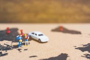 Miniature travelers walking on a world map, traveling and exploring the world concept photo