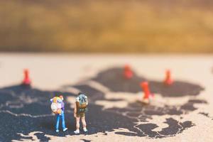 Miniature travelers walking on a world map, traveling and exploring the world concept photo