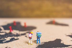 Miniature travelers walking on a world map, traveling and exploring the world concept photo