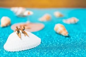 Gente en miniatura vistiendo trajes de baño relajándose en una concha con un fondo brillante