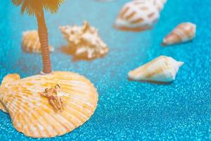 Miniature people wearing swimsuits relaxing on a seashell with a glitter background photo