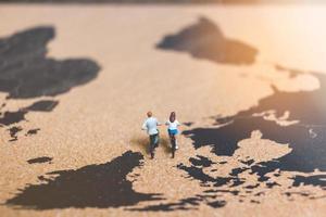 Miniature travelers riding bicycles on a world map, traveling and exploring the world concept photo