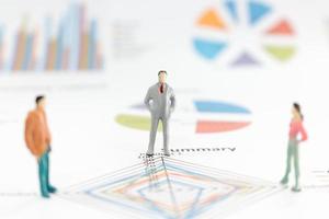 Miniature businesspeople standing on a graph chart photo