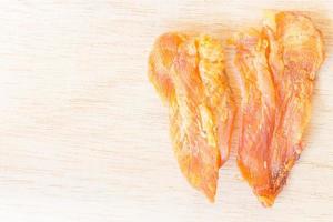 Dried chicken jerky for dogs on a wooden background photo