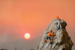 Excursionistas en miniatura subiendo a una roca, concepto deportivo y de ocio