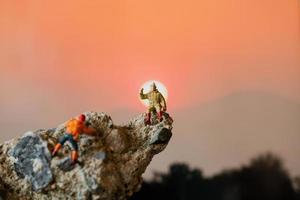 Excursionistas en miniatura subiendo a una roca, concepto deportivo y de ocio foto