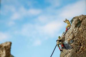 Excursionistas en miniatura subiendo a una roca, concepto deportivo y de ocio