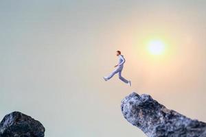 Miniature people running on a rock cliff with nature background, health and lifestyle concept photo