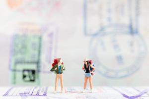 Miniature travelers with backpacks walking on a passport, travel and adventure concept photo