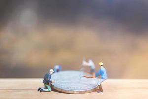 Trabajadores en miniatura ganando dinero sobre un fondo de madera foto