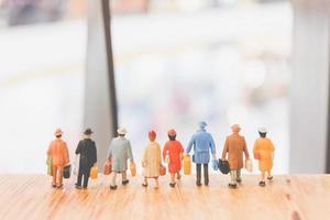 Miniature travelers walking on a wooden floor, holiday and travel concept photo