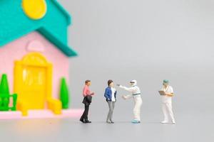 Miniature people with PPE visiting patients for a check for coronavirus at home, health care concept photo