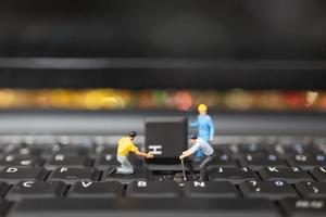 Miniature team of engineers repairing a keyboard computer laptop, computer repair concept photo