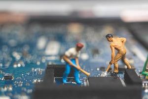 Equipo de ingenieros en miniatura que reparan una computadora portátil con teclado, concepto de reparación de computadoras foto