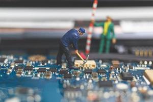 Miniature team of engineers repairing a keyboard computer laptop, computer repair concept photo