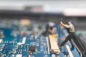 Equipo de ingenieros en miniatura que reparan una computadora portátil con teclado, concepto de reparación de computadoras foto