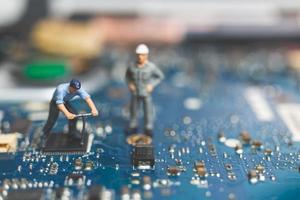 Miniature team of engineers repairing a keyboard computer laptop, computer repair concept photo