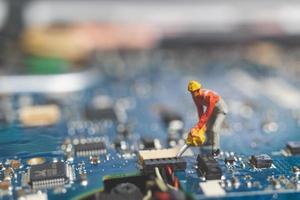 Miniature team of engineers repairing a keyboard computer laptop, computer repair concept photo