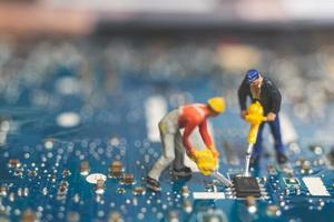 Equipo de ingenieros en miniatura que reparan una computadora portátil con teclado, concepto de reparación de computadoras foto