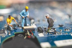 Miniature team of engineers repairing a keyboard computer laptop, computer repair concept photo