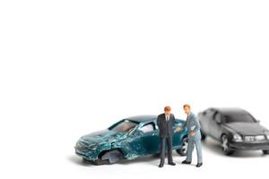 Personas en miniatura en la escena de un accidente automovilístico, accidente automovilístico sobre un fondo blanco, concepto de conducción segura foto