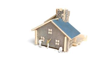 Miniature painters painting a wooden house on a white background photo