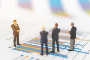 Miniature businessmen standing on charts photo