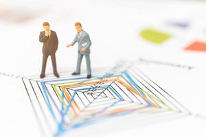 Miniature businessmen standing on charts photo