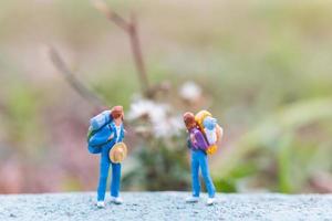 Miniature travelers with backpacks standing on a road, travel and trekking concept photo