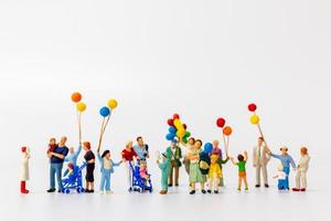 Miniature people holding balloons isolated on a white background photo