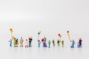 Personas en miniatura sosteniendo globos aislado sobre un fondo blanco. foto