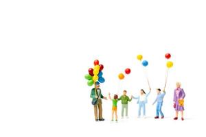 Miniature people holding balloons isolated on a white background