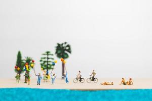 Miniature people enjoying summer vacation on the beach photo