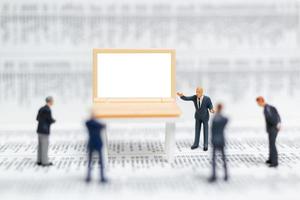 Miniature businesspeople thinking with a project for presenting investments on a white screen computer laptop, business and technology concept photo