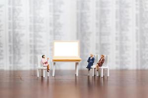 Miniature businesspeople thinking with a project for presenting investments on a white screen computer laptop, business and technology concept photo