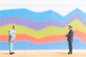 Miniature businessmen standing in front of a business graph background, business growth concept photo