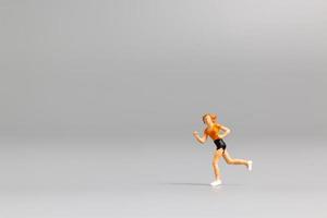 Miniature person running on a gray background photo