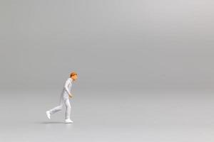 Miniature person running on a gray background photo