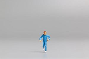 Miniature person running on a gray background photo