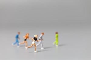 Miniature people running on a gray background photo