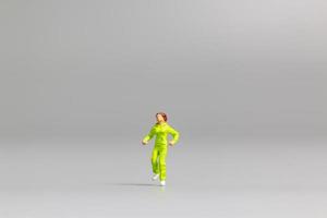 Miniature person running on a gray background photo