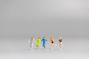 Miniature people running on a gray background photo