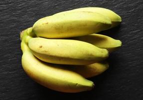 Small yellow bananas on black background photo