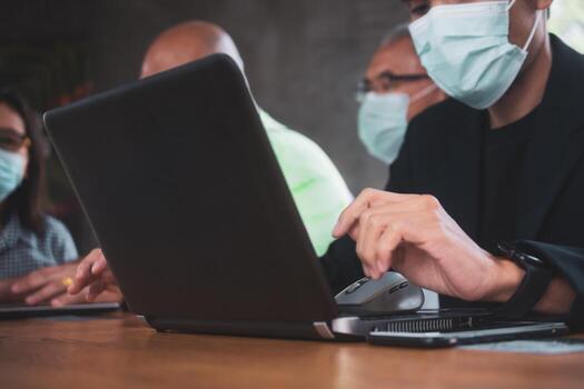 personas hablando en la oficina y trabajando con computadoras portátiles con máscaras para protegerse contra el covid-19 foto