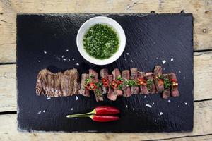 Black stone plate with skirt steak pepper and chimichurri sauce photo