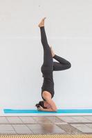 Hermosa mujer de yoga practicse en un fondo de sala de entrenamiento en la piscina foto