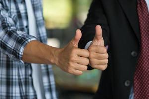 Close-up of young business man giving thumbs up at the office photo