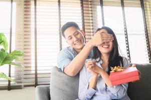 Asian man giving gift box present to surprise his girlfriend photo