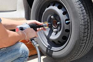 Man is changing a tire with wheel wrench photo